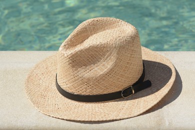 Photo of Stylish hat near outdoor swimming pool on sunny day. Beach accessory