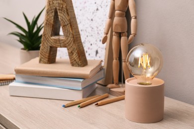 Photo of Modern night lamp, books and decor on table indoors. Space for text