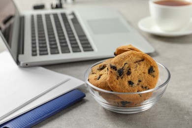 Photo of Bowl with chocolate chip cookies on light grey table in office, closeup. Space for text