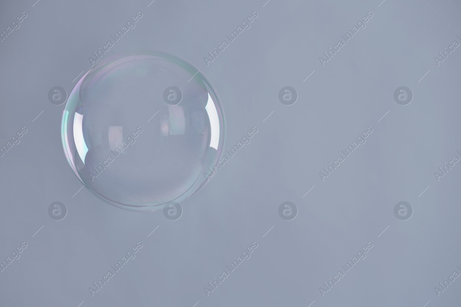 Photo of Beautiful translucent soap bubble on grey background. Space for text