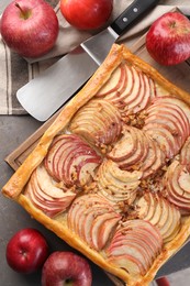 Photo of Tasty apple pie with nuts, fresh fruits and cake server on grey table, flat lay