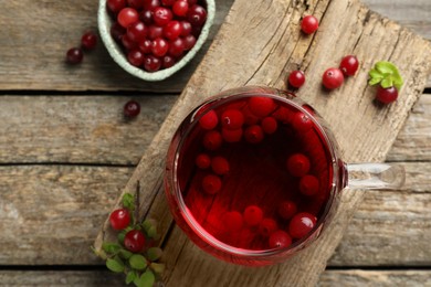 Photo of Delicious cranberry tea and berries on wooden table, flat lay