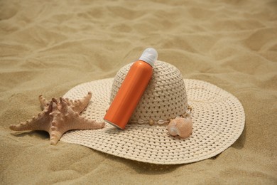 Photo of Sunscreen, hat and starfish on sand. Sun protection care