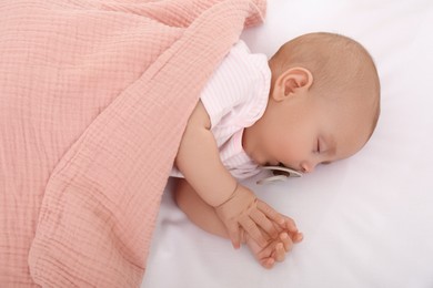 Photo of Cute little baby with pacifier sleeping under blanket, top view