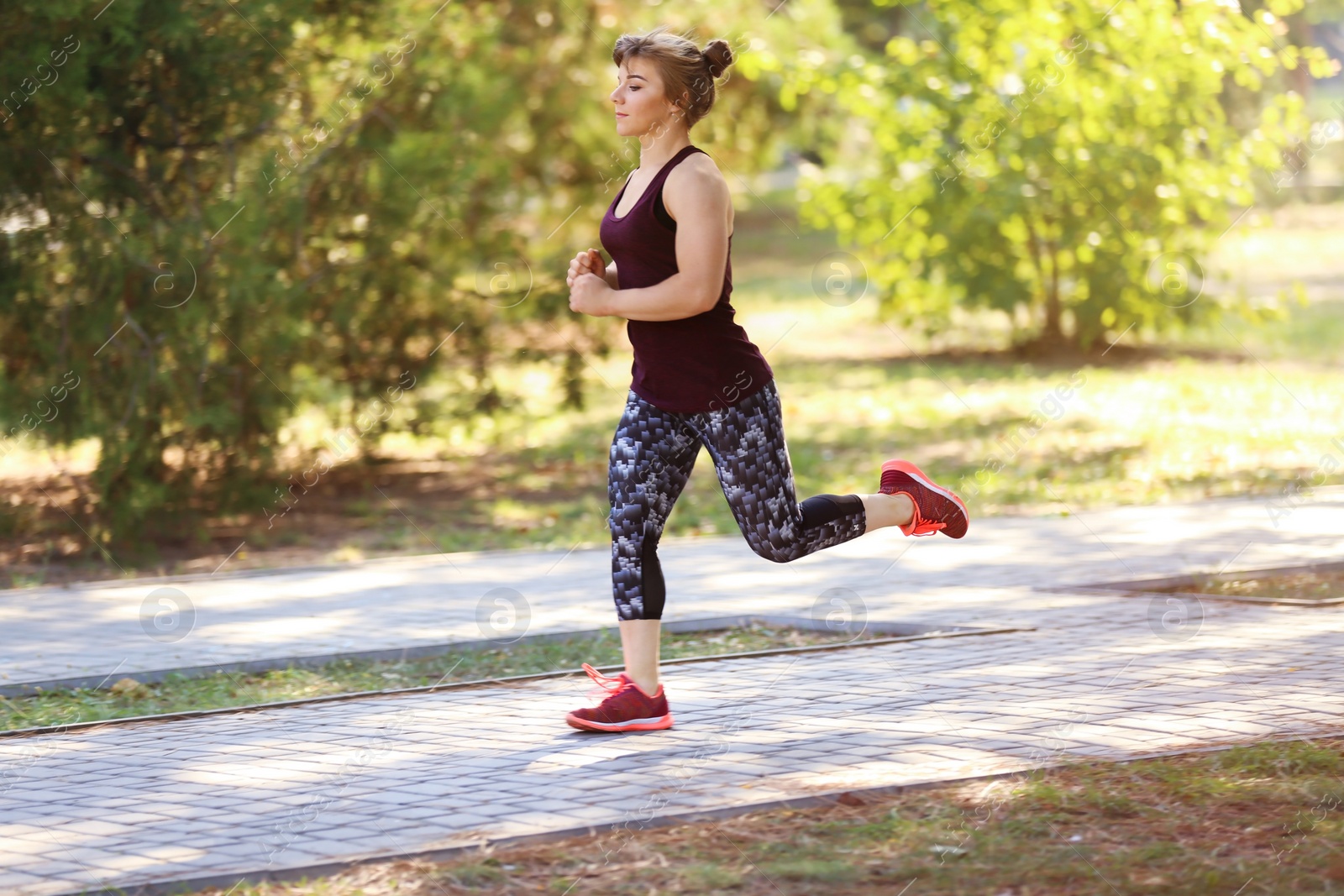 Photo of Young woman running in park on sunny day