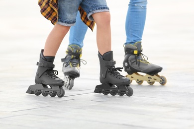 Photo of Father and son roller skating on city street, closeup of legs