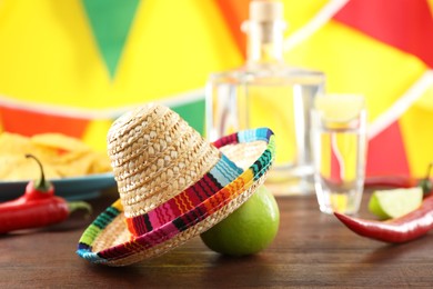 Mexican sombrero hat, lime and chili pepper on wooden table