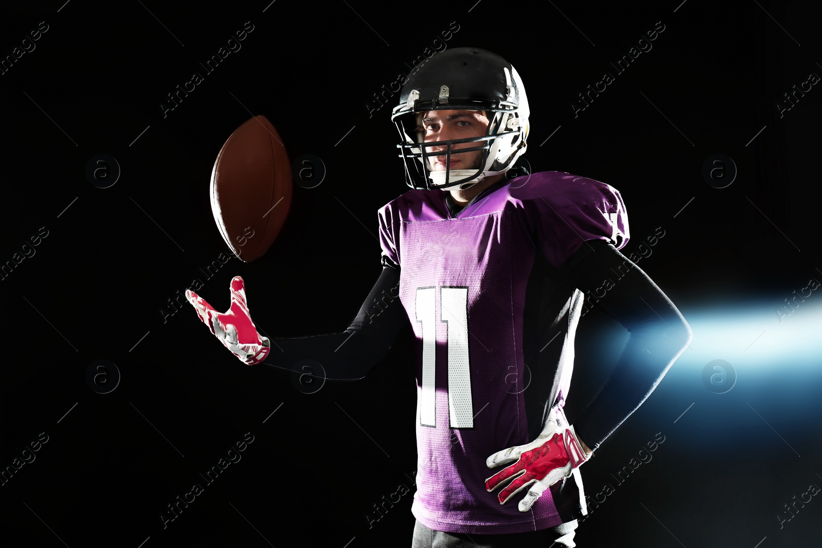 Photo of American football player with ball on dark background