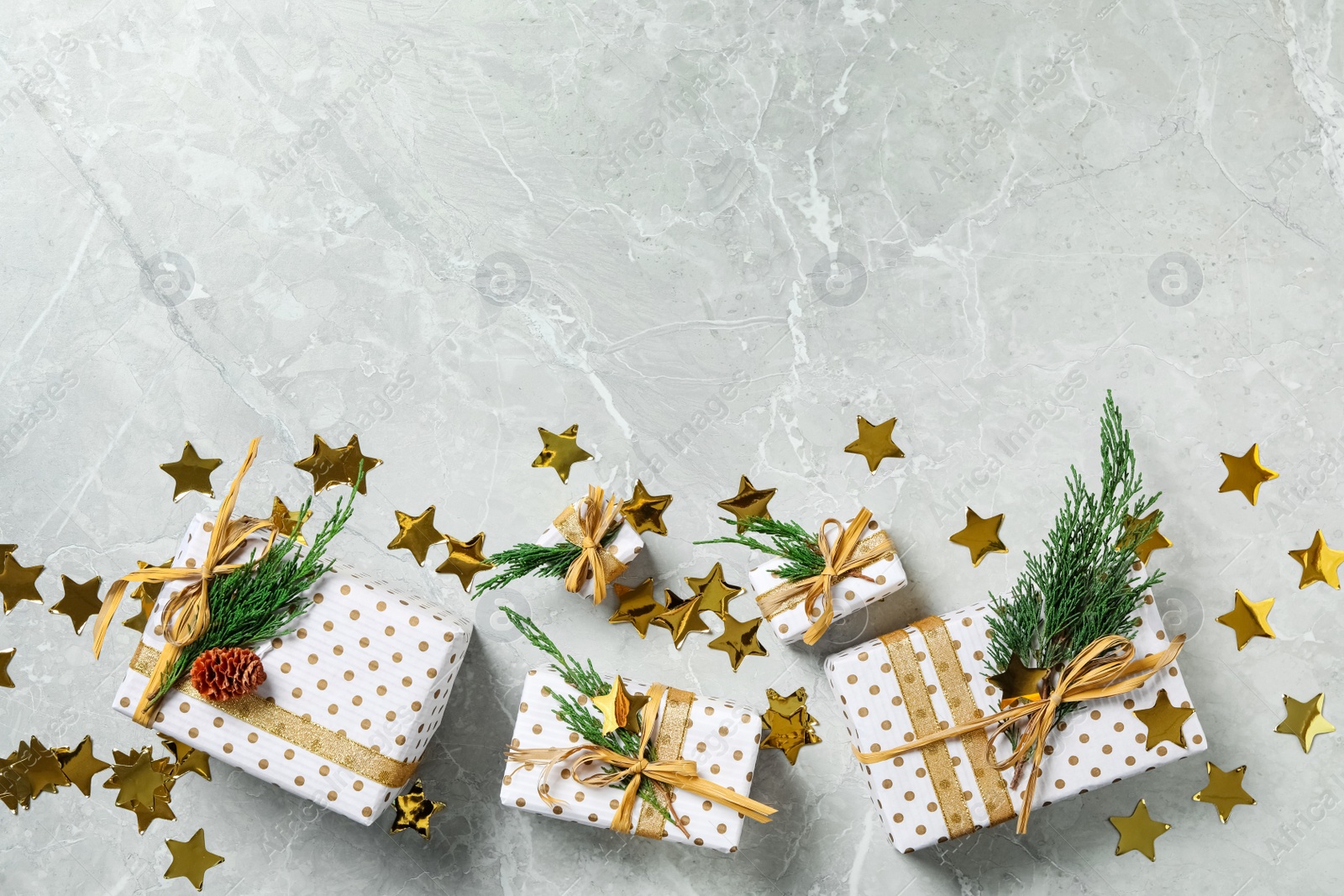 Photo of Christmas gift boxes with fir branches on light grey marble background, flat lay. Space for text