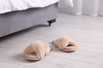 Photo of Beige soft slippers on light wooden floor at home