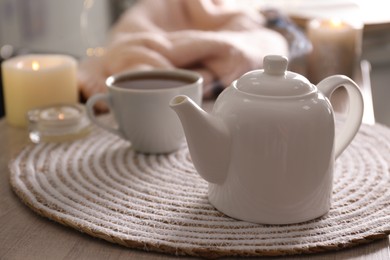 Photo of Teapot with cup of hot tea on table indoors