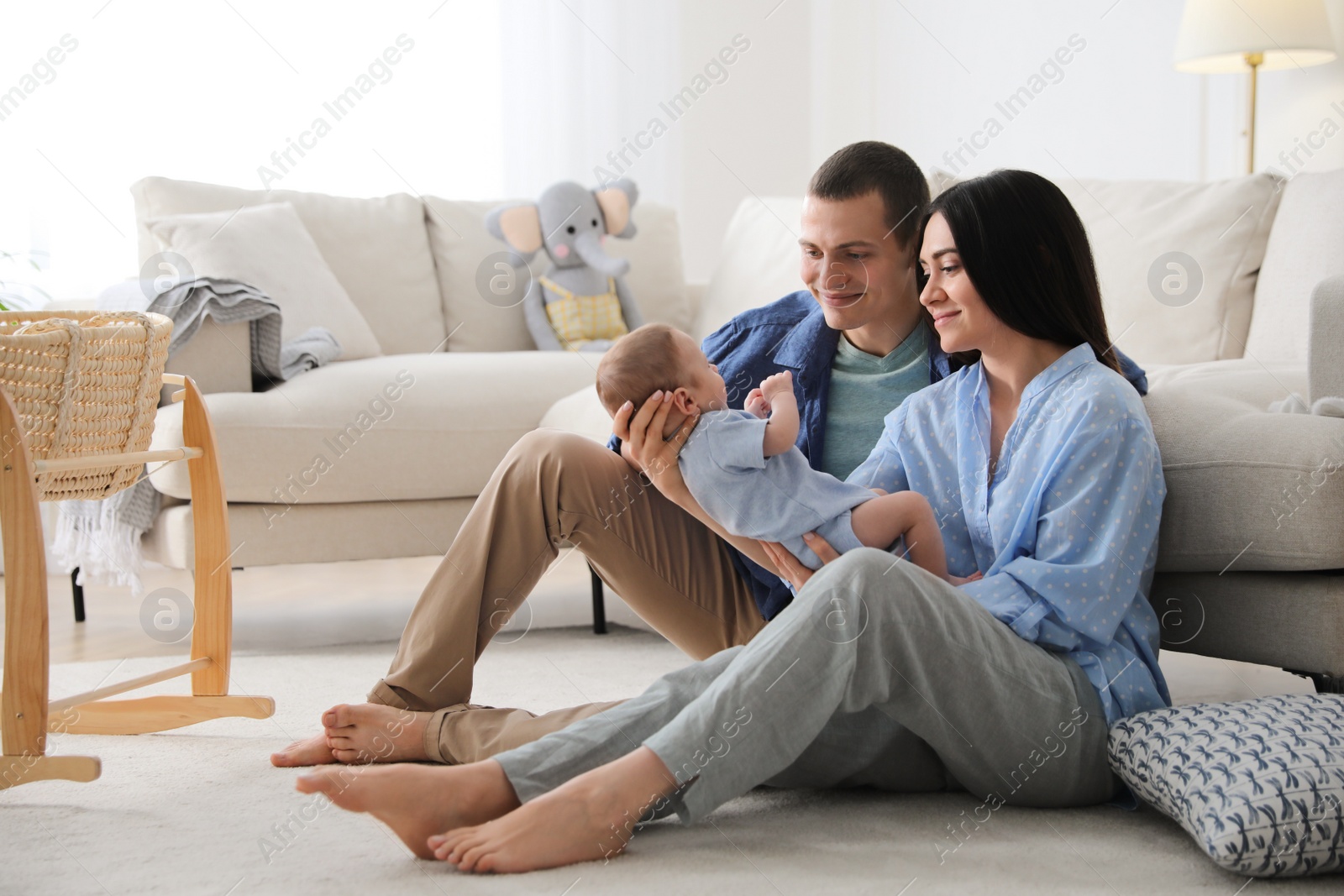 Photo of Happy family with cute baby near sofa at home