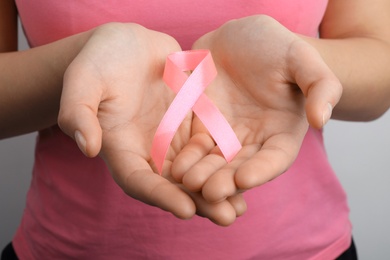 Woman holding pink ribbon, closeup. Breast cancer awareness