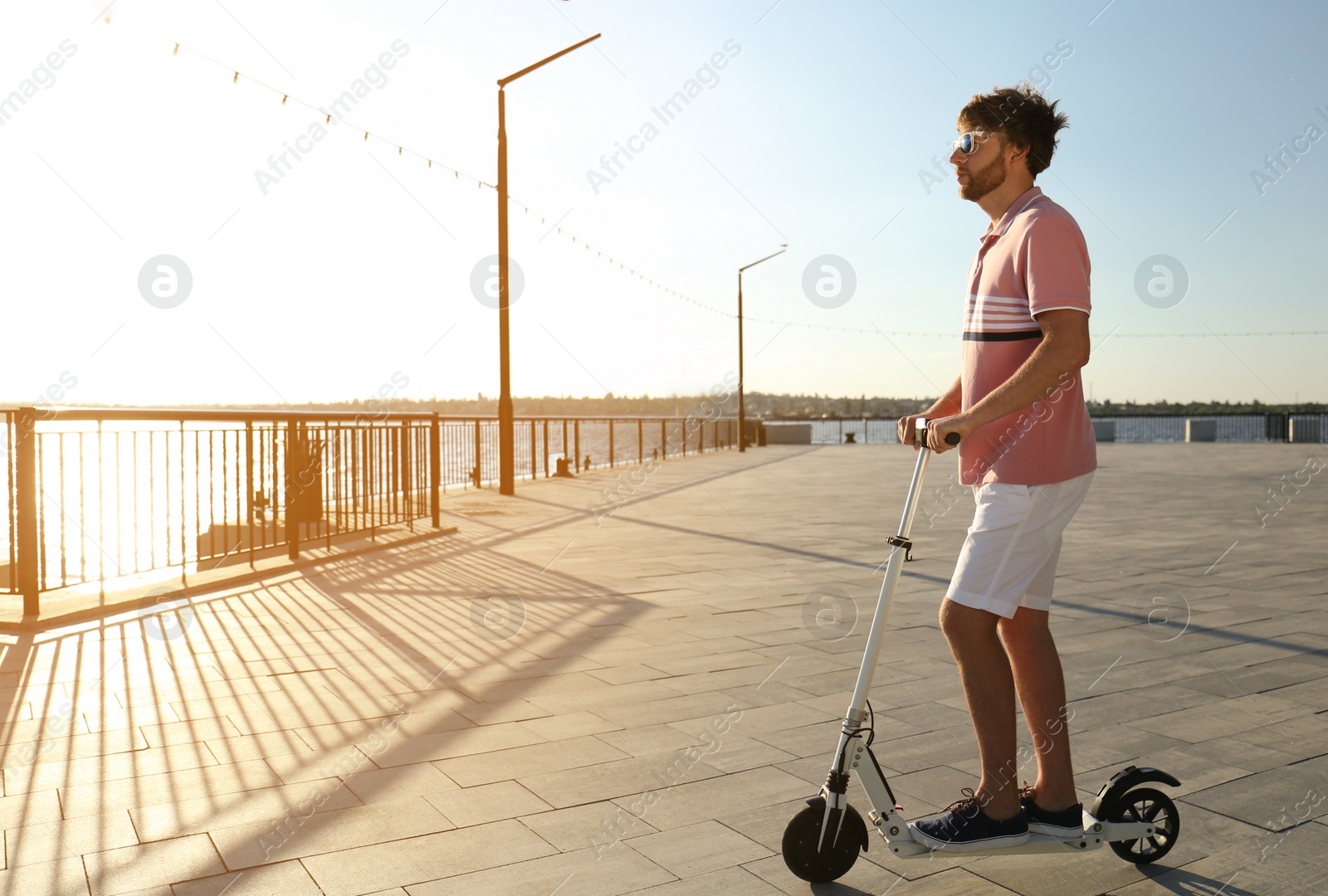 Photo of Man riding modern kick scooter along waterfront
