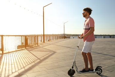 Photo of Man riding modern kick scooter along waterfront