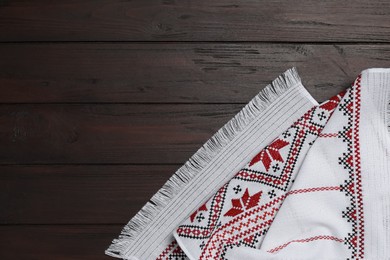 Photo of Beautiful rushnyk on wooden table, top view with space for text. Ukrainian national embroidery