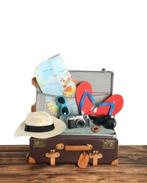 Photo of Open vintage suitcase with clothes packed for summer vacation on wooden table against white background