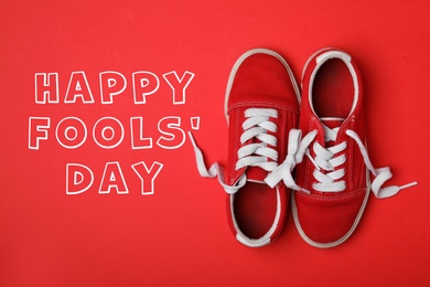 Image of Shoes tied together on red background, flat lay. Happy Fool's Day