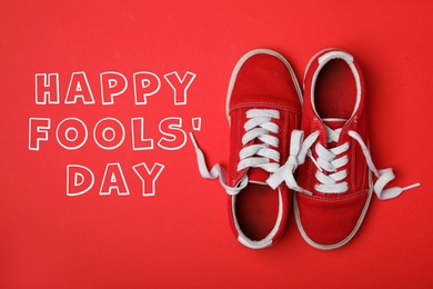 Shoes tied together on red background, flat lay. Happy Fool's Day