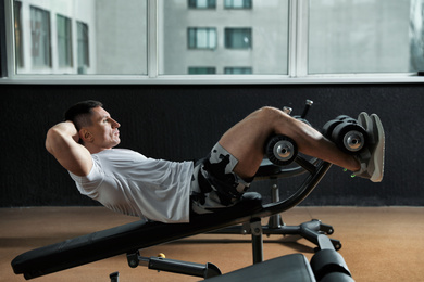 Man working out on adjustable sit up bench in modern gym
