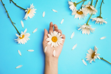 Photo of Woman with beautiful chamomile flowers on color background, top view