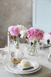 Photo of Stylish table setting with beautiful peonies and burning candles indoors