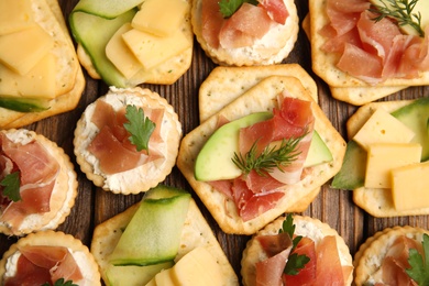 Photo of Different snacks with salted crackers on wooden table, flat lay