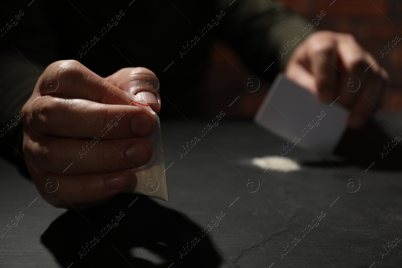 Photo of Addicted man with hard drug and blank card preparing for consumption at grey table, selective focus