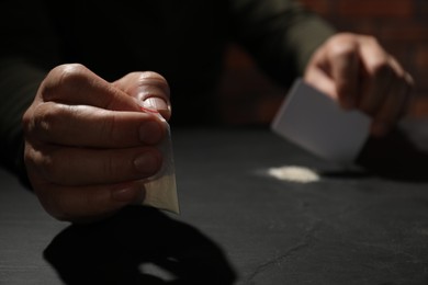 Photo of Addicted man with hard drug and blank card preparing for consumption at grey table, selective focus