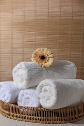 Photo of Rolled terry towels and flower on white table indoors