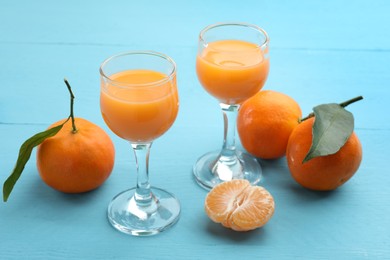 Delicious tangerine liqueur and fresh fruits on light blue wooden table