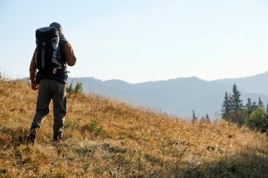Photo of Tourist with backpack in mountains, back view. Space for text