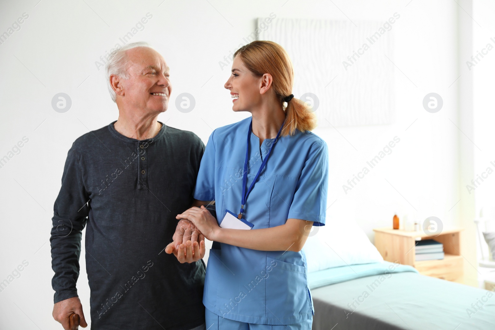 Photo of Nurse in uniform assisting elderly woman indoors