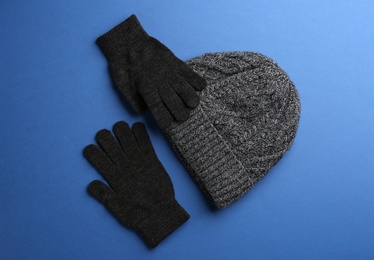 Woolen gloves and hat on blue background, flat lay