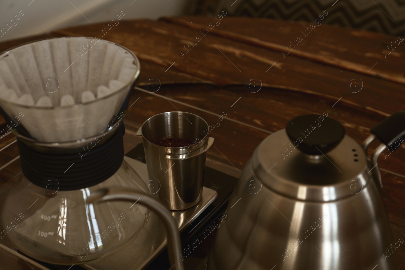 Photo of Cup with coffee, wave dripper and kettle on wooden table in cafe