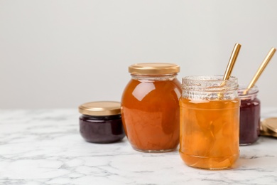 Photo of Jars with different sweet jam on table