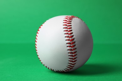 Photo of One baseball ball with stitches on green background