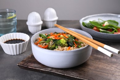 Photo of Tasty fried rice with vegetables served on grey table, closeup