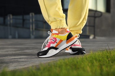 Photo of Woman wearing pair of stylish sneakers outdoors, closeup