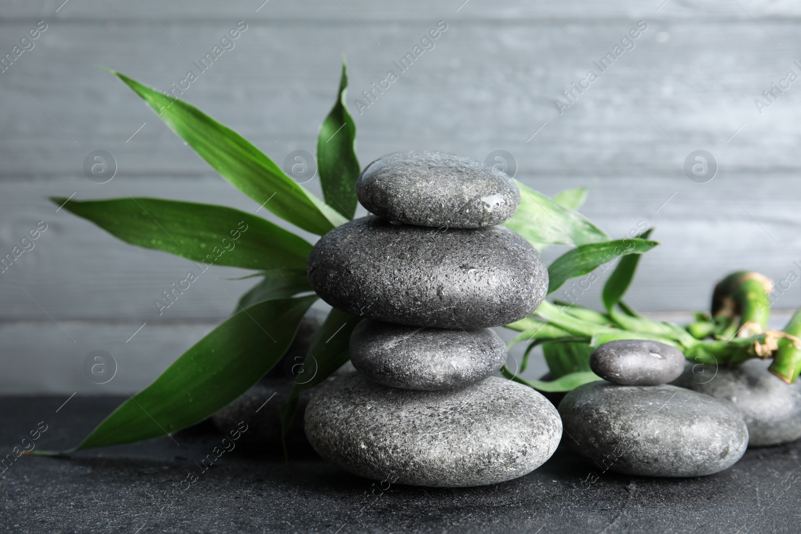 Photo of Stacked zen stones and bamboo leaves on table against wooden background