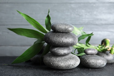 Photo of Stacked zen stones and bamboo leaves on table against wooden background