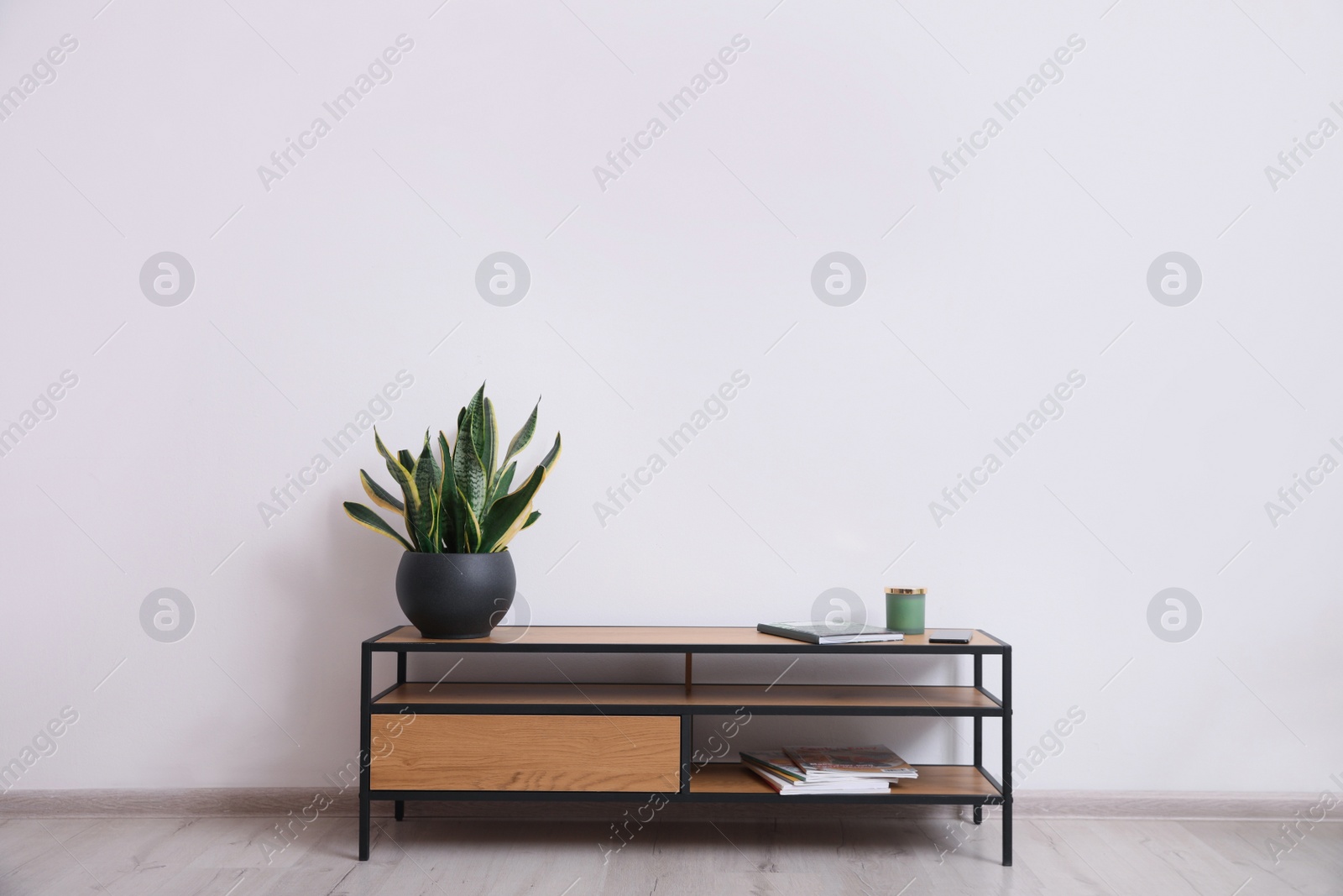 Photo of Elegant room interior with wooden cabinet and beautiful houseplant near white wall