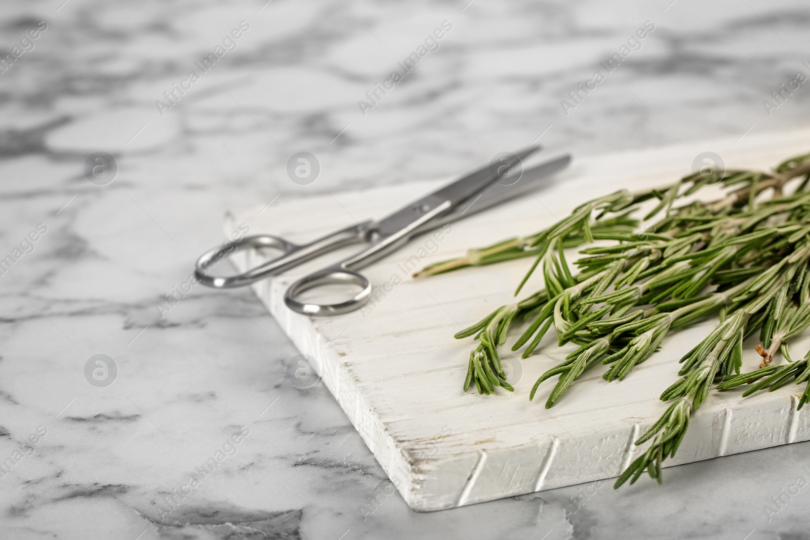 Photo of Board with fresh rosemary twigs on table, closeup