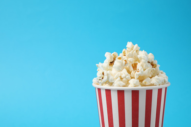 Photo of Delicious popcorn on light blue background, closeup. Space for text