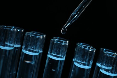 Photo of Dripping reagent into test tube on black background, closeup. Laboratory analysis