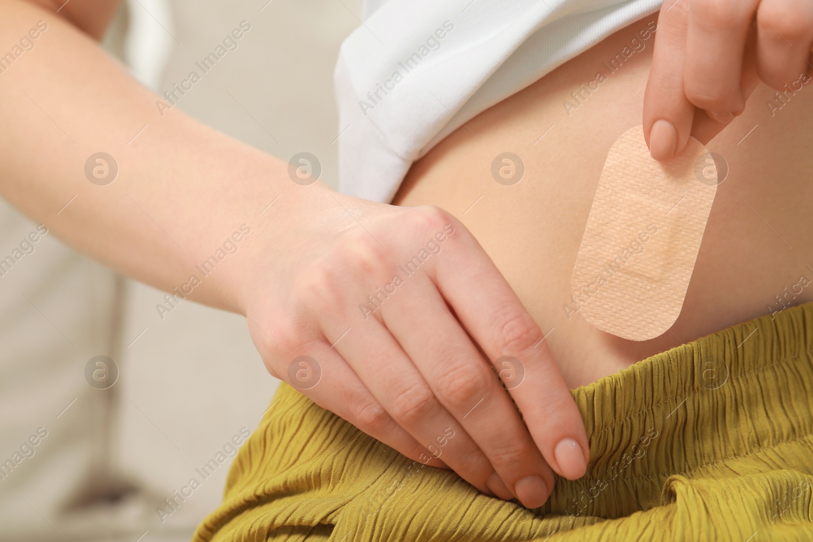 Photo of Woman applying contraceptive patch onto her body, closeup