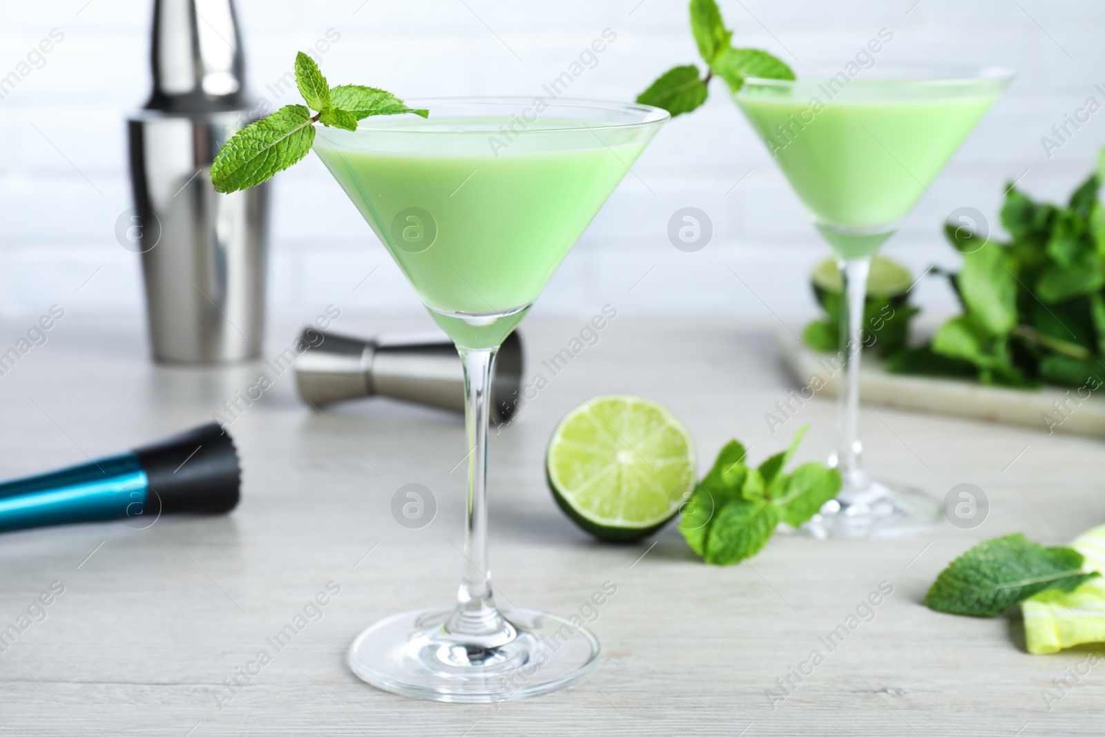 Photo of Delicious mint liqueur with green leaves on white wooden table