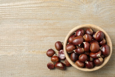 Photo of Fresh sweet edible chestnuts on wooden table, flat lay. Space for text