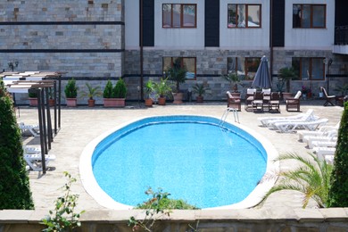 Sunbeds and outdoor swimming pool near building on sunny day