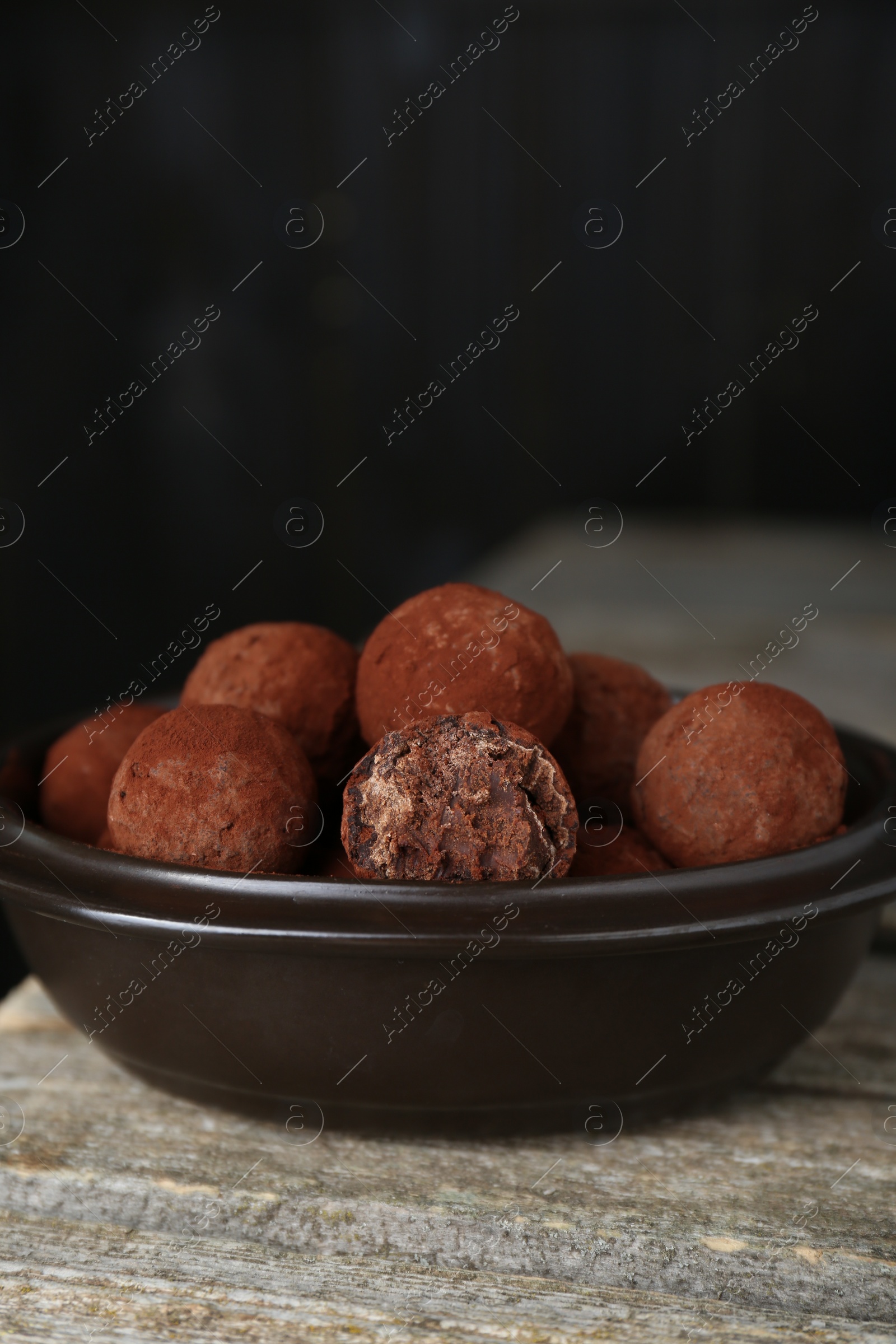 Photo of Delicious chocolate candies powdered with cocoa on wooden table